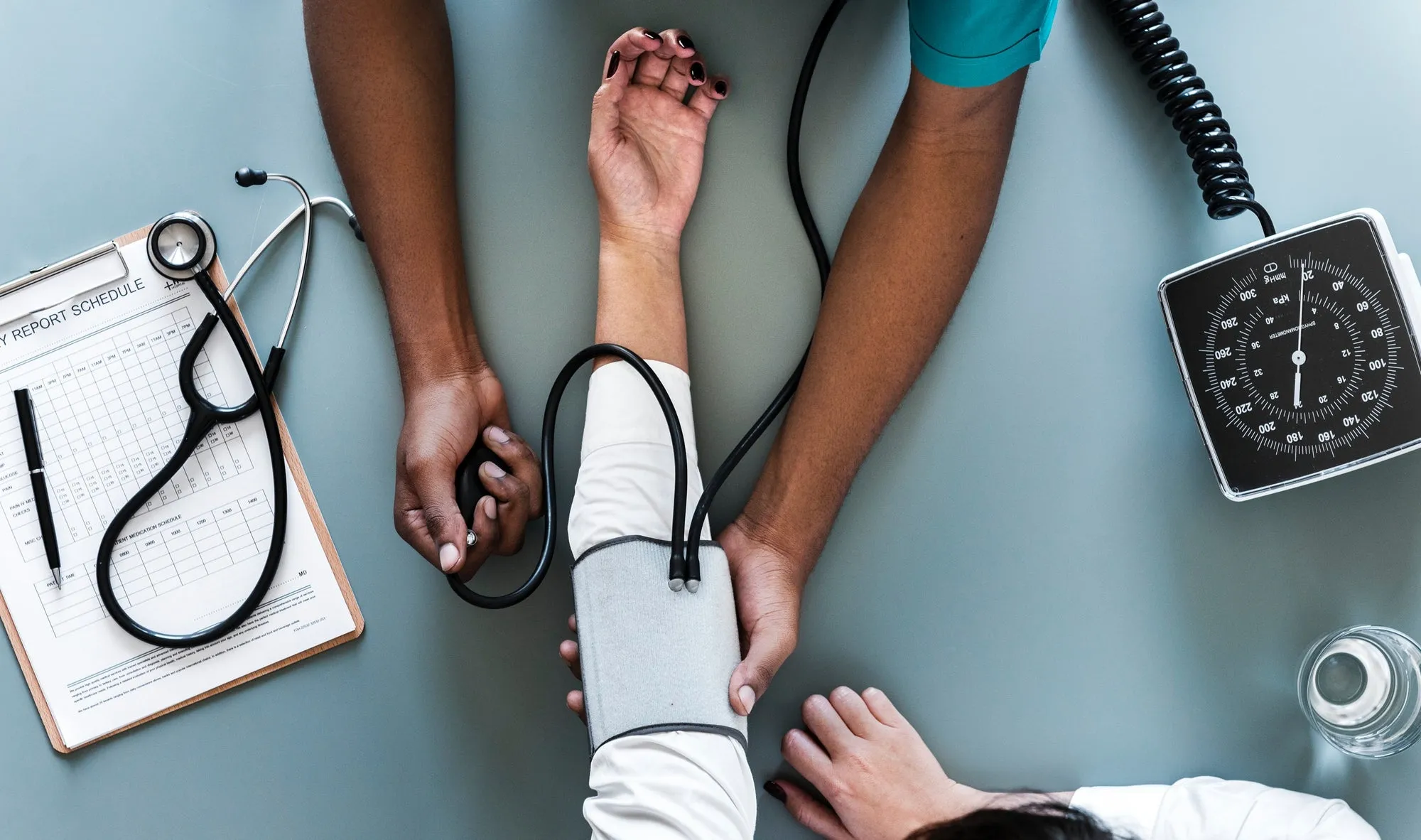 A clinician taking a patient's blood pressure during a routine exam. The kind of everyday clinical encounter where bias most often shapes outcomes.